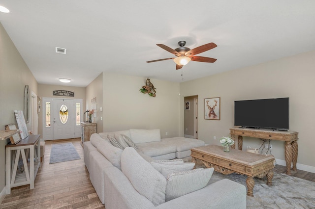 living area featuring light wood-style flooring, baseboards, a ceiling fan, and visible vents