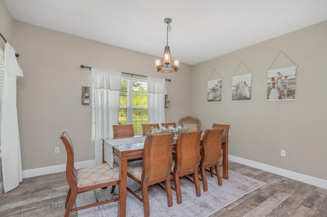 dining room with light wood-style floors, baseboards, and a notable chandelier