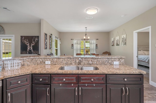 kitchen with an inviting chandelier, visible vents, wood finished floors, and a sink