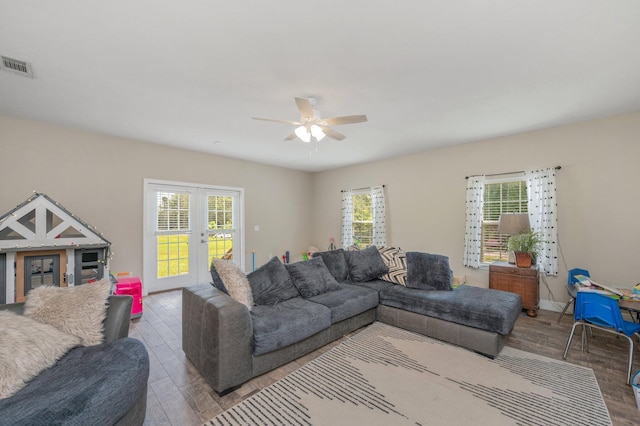 living area with a ceiling fan, french doors, visible vents, and wood finished floors