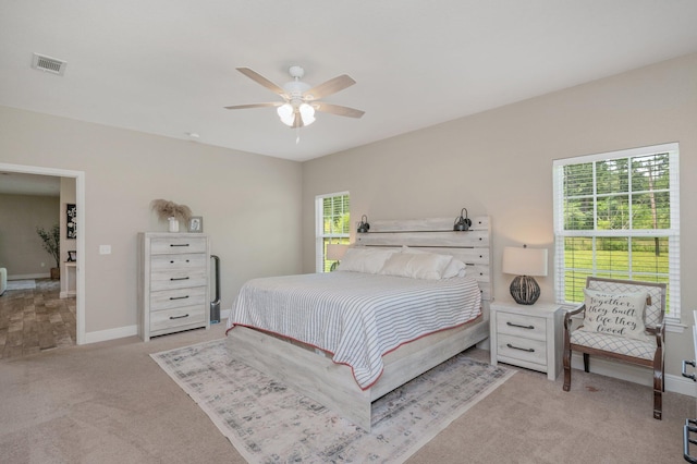 bedroom featuring light colored carpet, visible vents, baseboards, and a ceiling fan