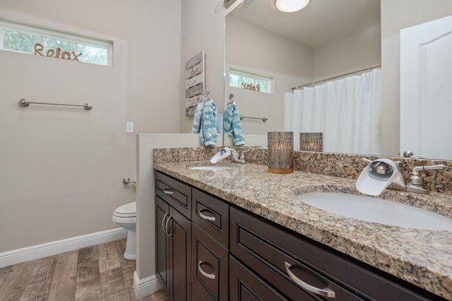 full bath with toilet, a wealth of natural light, baseboards, and a sink