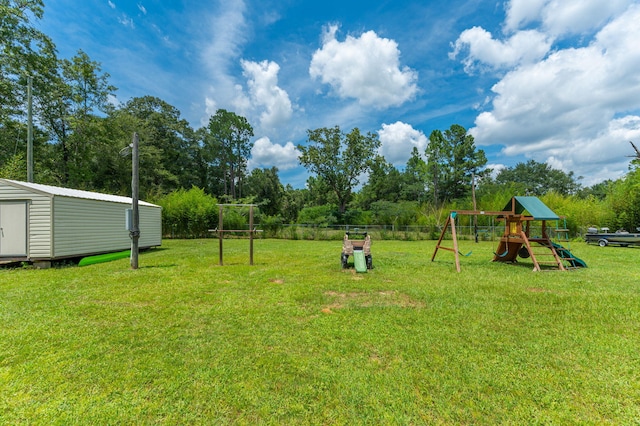 view of yard with a storage unit, fence, a playground, and an outbuilding