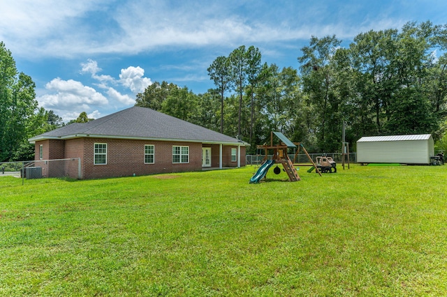 back of property with a yard, fence, and a storage unit