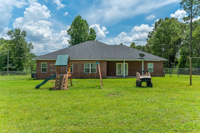 rear view of property with a playground, a yard, french doors, and a fenced backyard