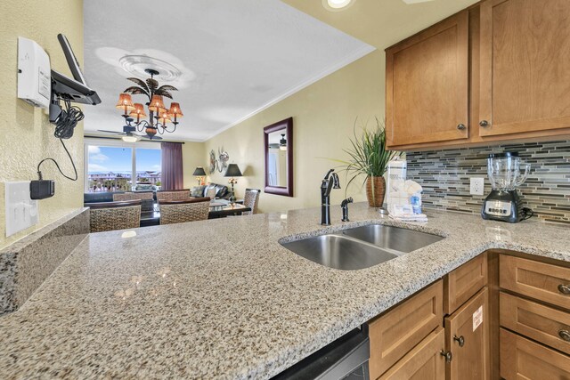502 Gulf Shore Dr Unit 413, Destin, FL 32541 - kitchen with a sink, a chandelier, a peninsula, light stone counters, and decorative backsplash