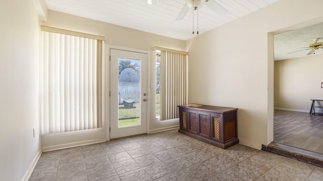 doorway with ceiling fan, baseboards, and plenty of natural light