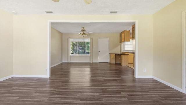 unfurnished living room with baseboards, dark wood-style flooring, visible vents, and ceiling fan