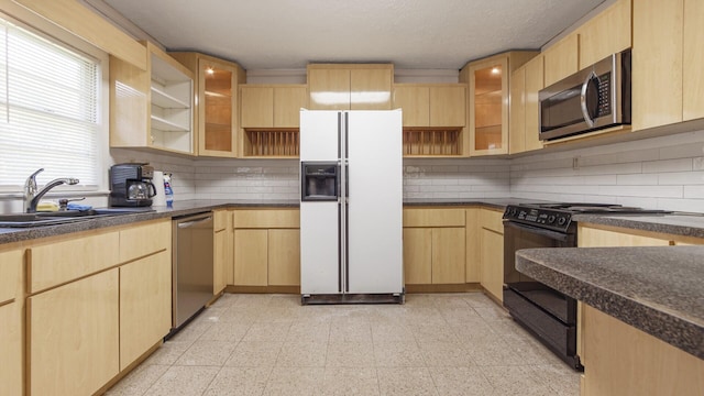 kitchen with a sink, open shelves, light brown cabinetry, dark countertops, and appliances with stainless steel finishes