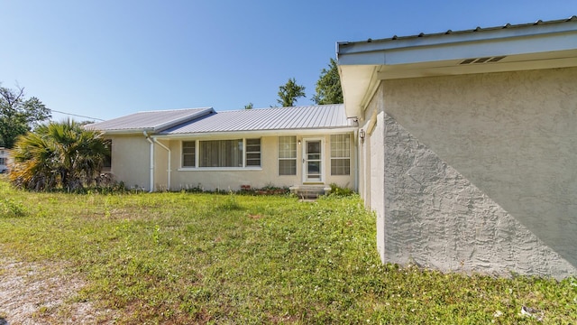 view of home's exterior with a lawn, stucco siding, and metal roof