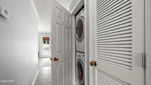 17690 Front Beach Rd Unit C105, Panama City Beach, FL 32413 - laundry room with stacked washer / dryer, a textured ceiling, baseboards, wood finished floors, and laundry area