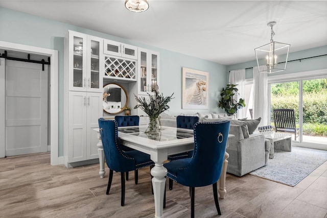 515 Topsl Beach Blvd # 106, Miramar Beach, FL 32550 - dining space featuring a chandelier, a barn door, and light wood-type flooring