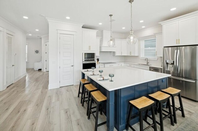 kitchen with appliances with stainless steel finishes, crown molding, a sink, a breakfast bar area, and a kitchen island
