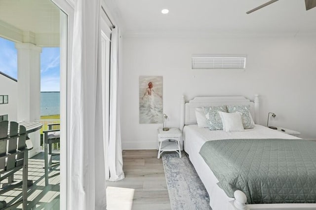 bedroom with ornamental molding, wood finished floors, a water view, baseboards, and recessed lighting