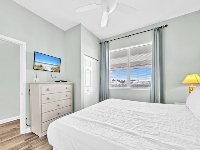 bedroom with wood finished floors, ceiling fan, a closet, and baseboards