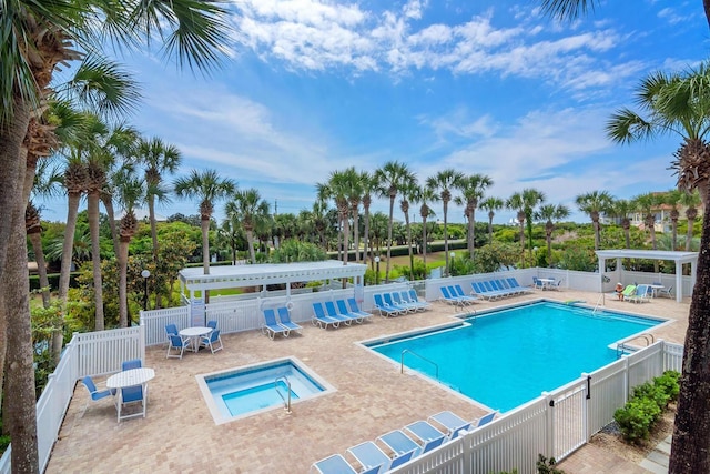 community pool featuring a hot tub, a patio area, fence, a pergola, and view of scattered trees