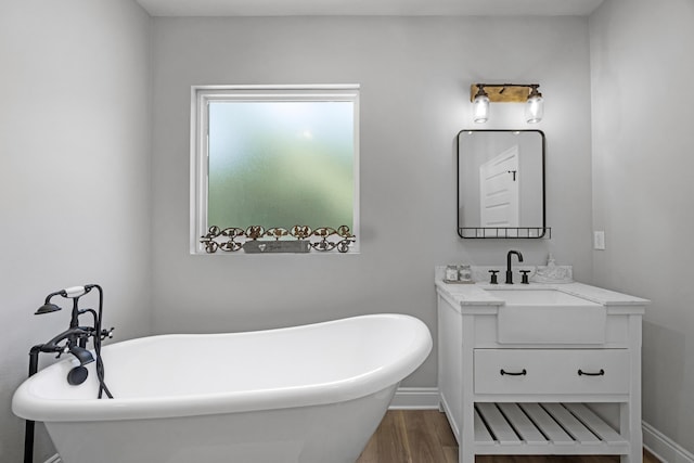 5881 Stacy Ln, Crestview, FL 32536 - bathroom featuring vanity, wood finished floors, a freestanding bath, and baseboards
