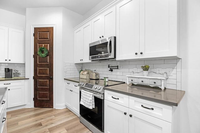 5881 Stacy Ln, Crestview, FL 32536 - kitchen featuring stainless steel appliances, dark countertops, decorative backsplash, light wood-type flooring, and white cabinets
