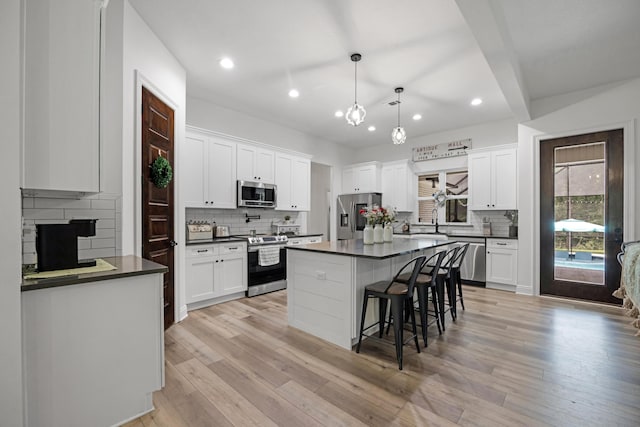 5881 Stacy Ln, Crestview, FL 32536 - kitchen with stainless steel appliances, dark countertops, backsplash, a breakfast bar, and white cabinetry