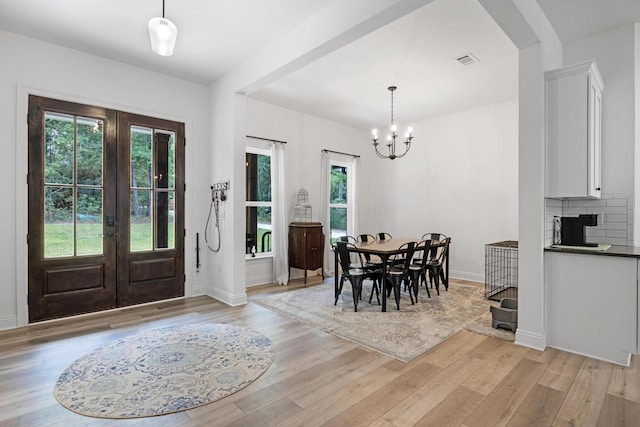 5881 Stacy Ln, Crestview, FL 32536 - dining space with french doors, light wood-style floors, a chandelier, baseboards, and arched walkways