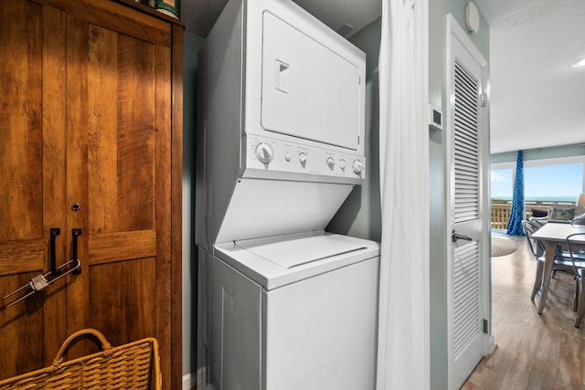 8294 E County Highway 30a Unit 1, Alys Beach, FL 32461 - laundry area with stacked washing machine and dryer and light wood-style flooring