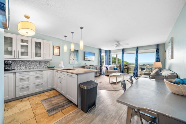 8294 E County Highway 30a Unit 1, Alys Beach, FL 32461 - kitchen featuring open floor plan, a peninsula, a sink, white cabinetry, and decorative backsplash
