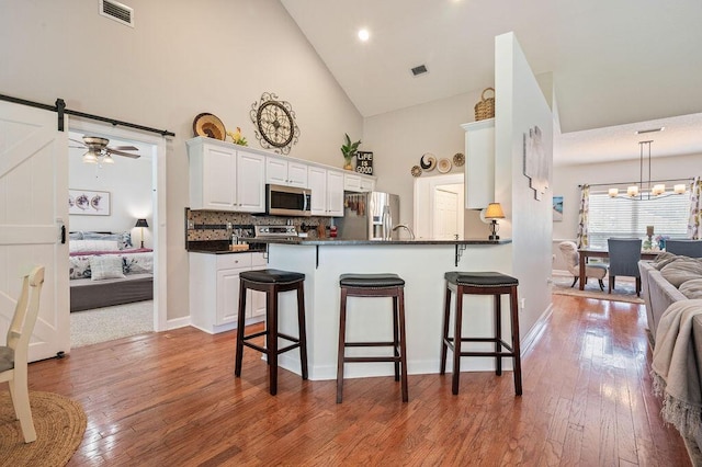 4475 New Market Rd, Niceville, FL 32578 - kitchen featuring appliances with stainless steel finishes, high vaulted ceiling, a breakfast bar, dark countertops, and white cabinetry