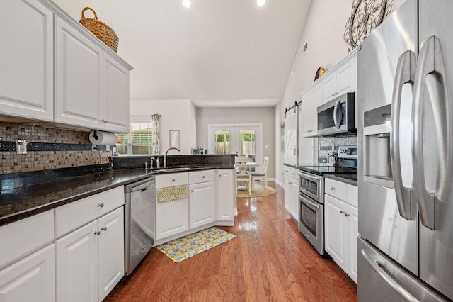 4475 New Market Rd, Niceville, FL 32578 - kitchen featuring stainless steel appliances, a sink, white cabinets, vaulted ceiling, and tasteful backsplash