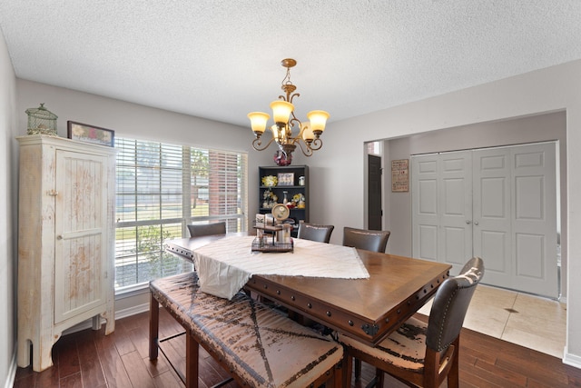 dining area with a chandelier, dark wood-type flooring, and a textured ceiling