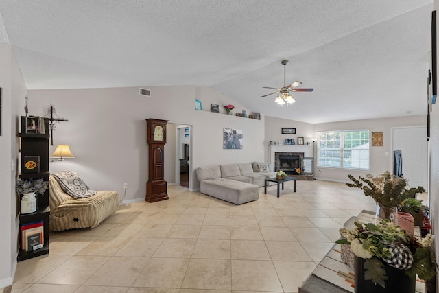 living room featuring ceiling fan, lofted ceiling, light tile patterned floors, a fireplace, and baseboards