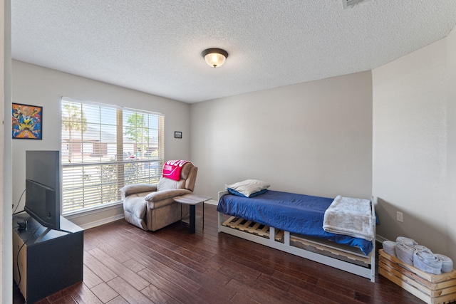 bedroom with dark wood-type flooring, a textured ceiling, and baseboards