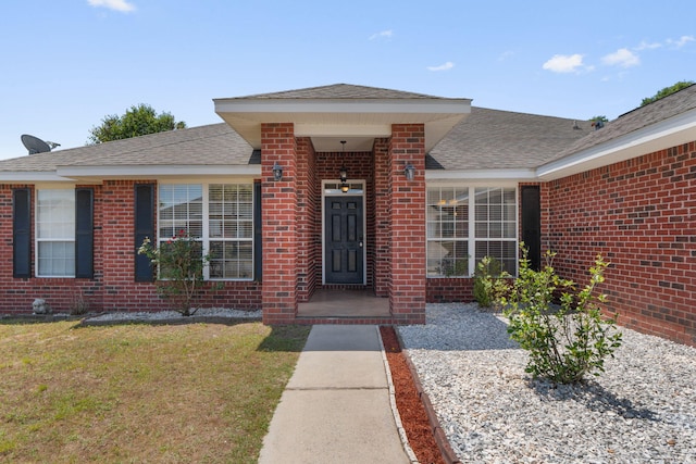 view of front of house with brick siding, roof with shingles, and a front lawn