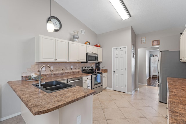kitchen with stainless steel appliances, a sink, decorative backsplash, a peninsula, and white cabinetry
