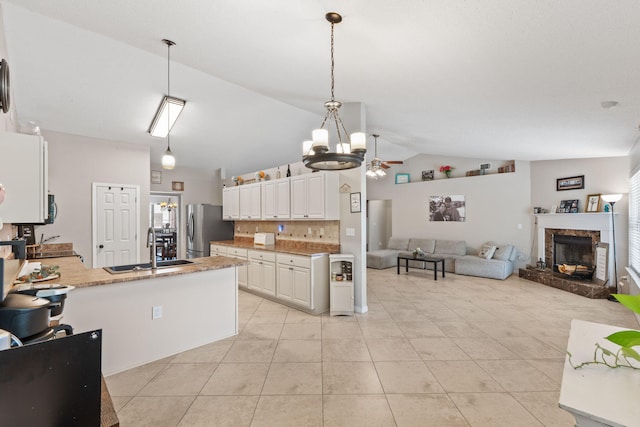 kitchen featuring freestanding refrigerator, a sink, a chandelier, backsplash, and open floor plan