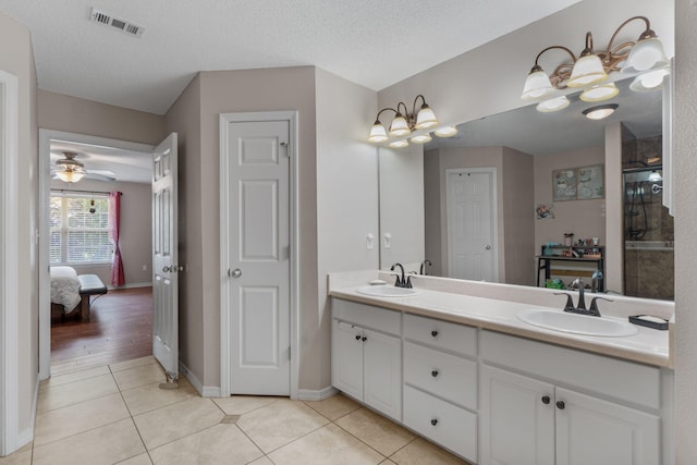 ensuite bathroom with double vanity, tile patterned floors, baseboards, an enclosed shower, and a ceiling fan