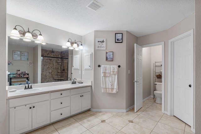 full bath featuring toilet, tiled shower, a textured ceiling, double vanity, and tile patterned floors