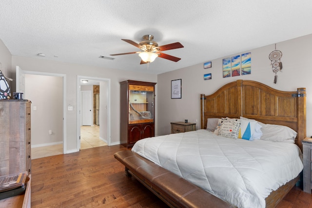 bedroom featuring hardwood / wood-style floors, ceiling fan, a textured ceiling, and baseboards