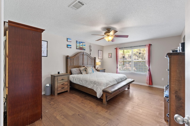 bedroom featuring wood finished floors, a textured ceiling, a ceiling fan, and baseboards
