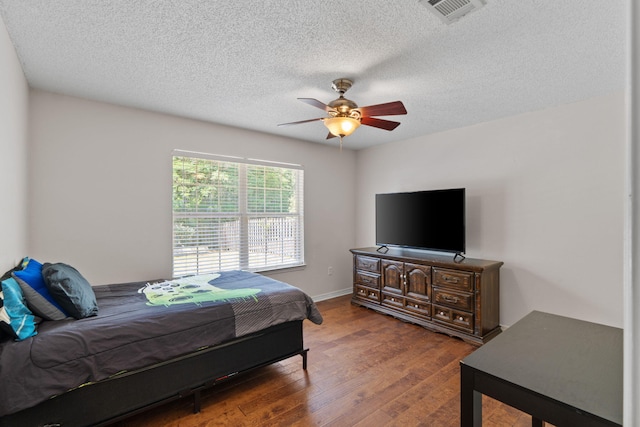 bedroom featuring wood finished floors, a textured ceiling, a ceiling fan, and baseboards