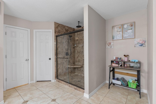 full bathroom featuring a stall shower, tile patterned flooring, baseboards, and a textured ceiling