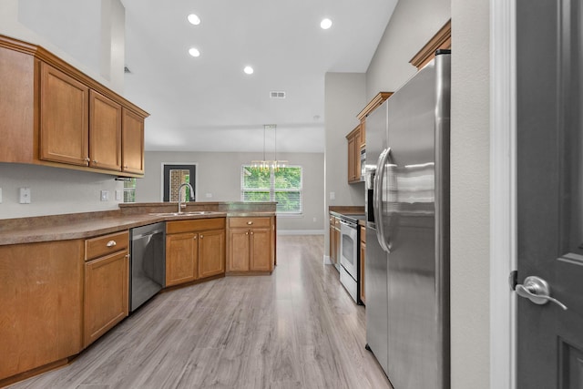 2354 Barberee Dr, Crestview, FL 32536 - kitchen with stainless steel appliances, a peninsula, a sink, light wood finished floors, and brown cabinetry