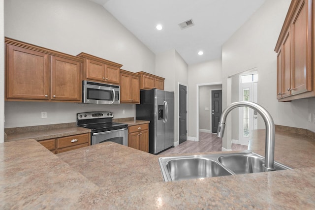 2354 Barberee Dr, Crestview, FL 32536 - kitchen featuring stainless steel appliances, a sink, high vaulted ceiling, brown cabinets, and light countertops