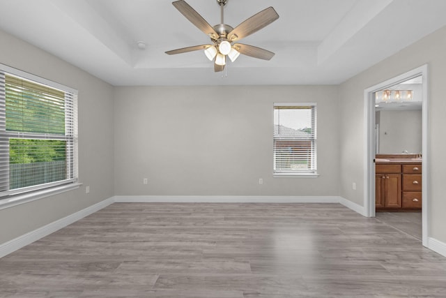 2354 Barberee Dr, Crestview, FL 32536 - unfurnished bedroom with a raised ceiling, light wood finished floors, baseboards, connected bathroom, and ceiling fan