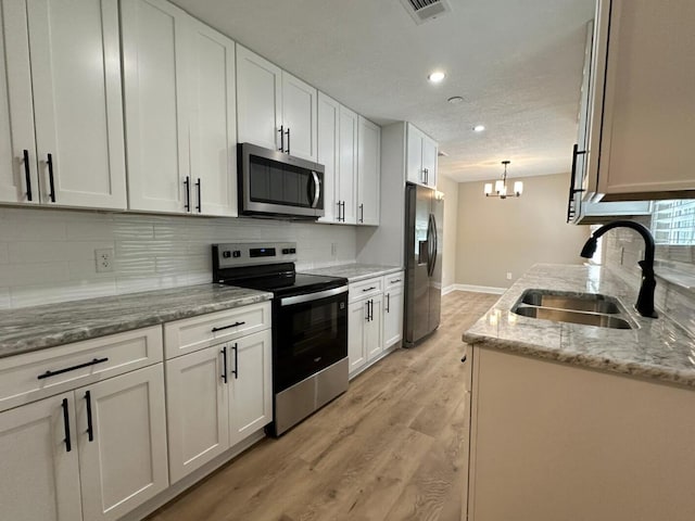 86 Poston Rd, Defuniak Springs, FL 32433 - kitchen with appliances with stainless steel finishes, a sink, light wood-style flooring, a chandelier, and backsplash