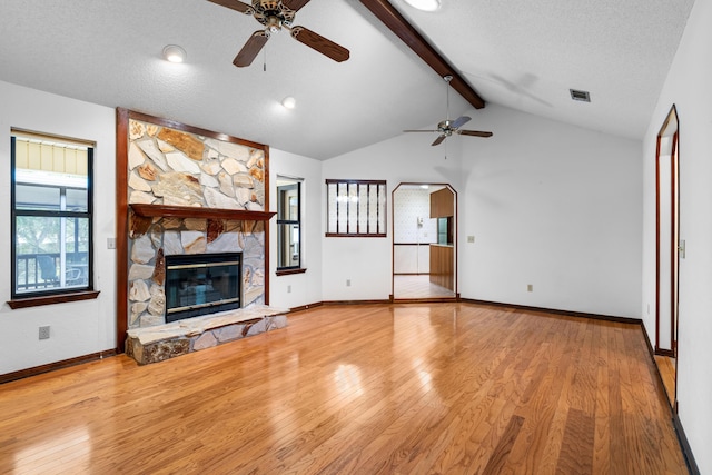 102 Bermuda Way, Niceville, FL 32578 - unfurnished living room with a ceiling fan, wood finished floors, a stone fireplace, baseboards, and a textured ceiling