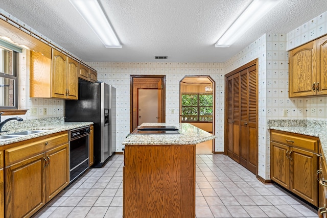 102 Bermuda Way, Niceville, FL 32578 - kitchen featuring wallpapered walls, a textured ceiling, a kitchen island, black dishwasher, and cooktop