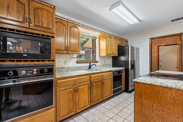 102 Bermuda Way, Niceville, FL 32578 - kitchen with black appliances, wallpapered walls, a sink, a textured ceiling, and brown cabinets