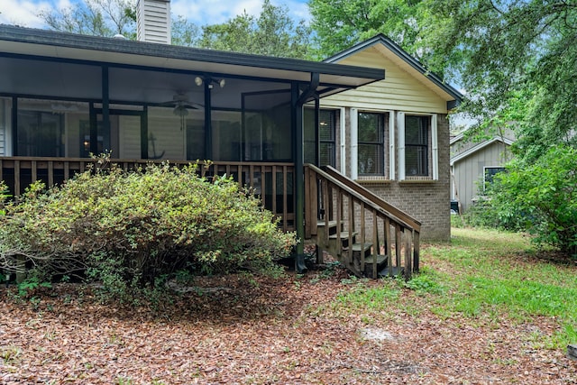 102 Bermuda Way, Niceville, FL 32578 - back of house featuring a sunroom, brick siding, a chimney, ceiling fan, and stairway