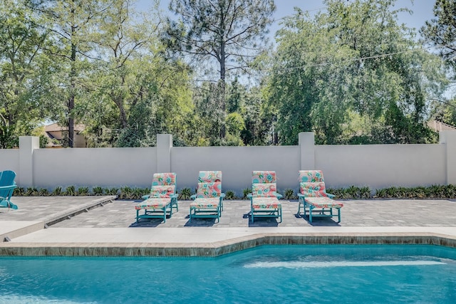 view of swimming pool featuring a patio and fence
