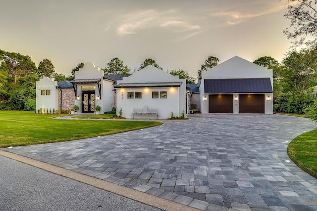 view of front of property with a standing seam roof, french doors, metal roof, decorative driveway, and stucco siding